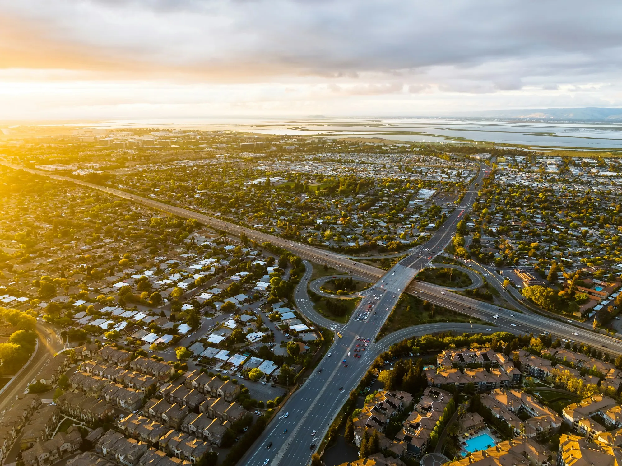 Aerial view of suburban neighborhoods and a freeway interchange at sunset
