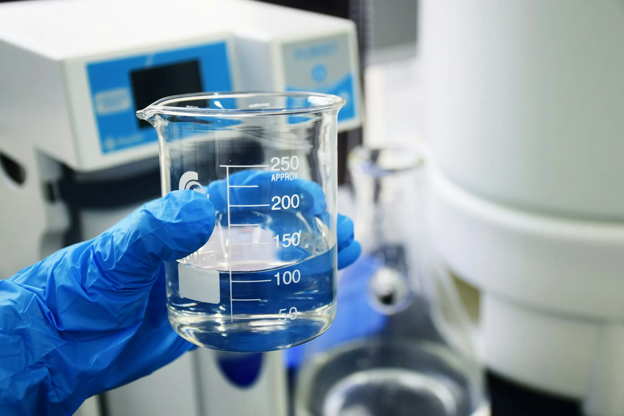 Gloved hand holding a beaker of water for testing