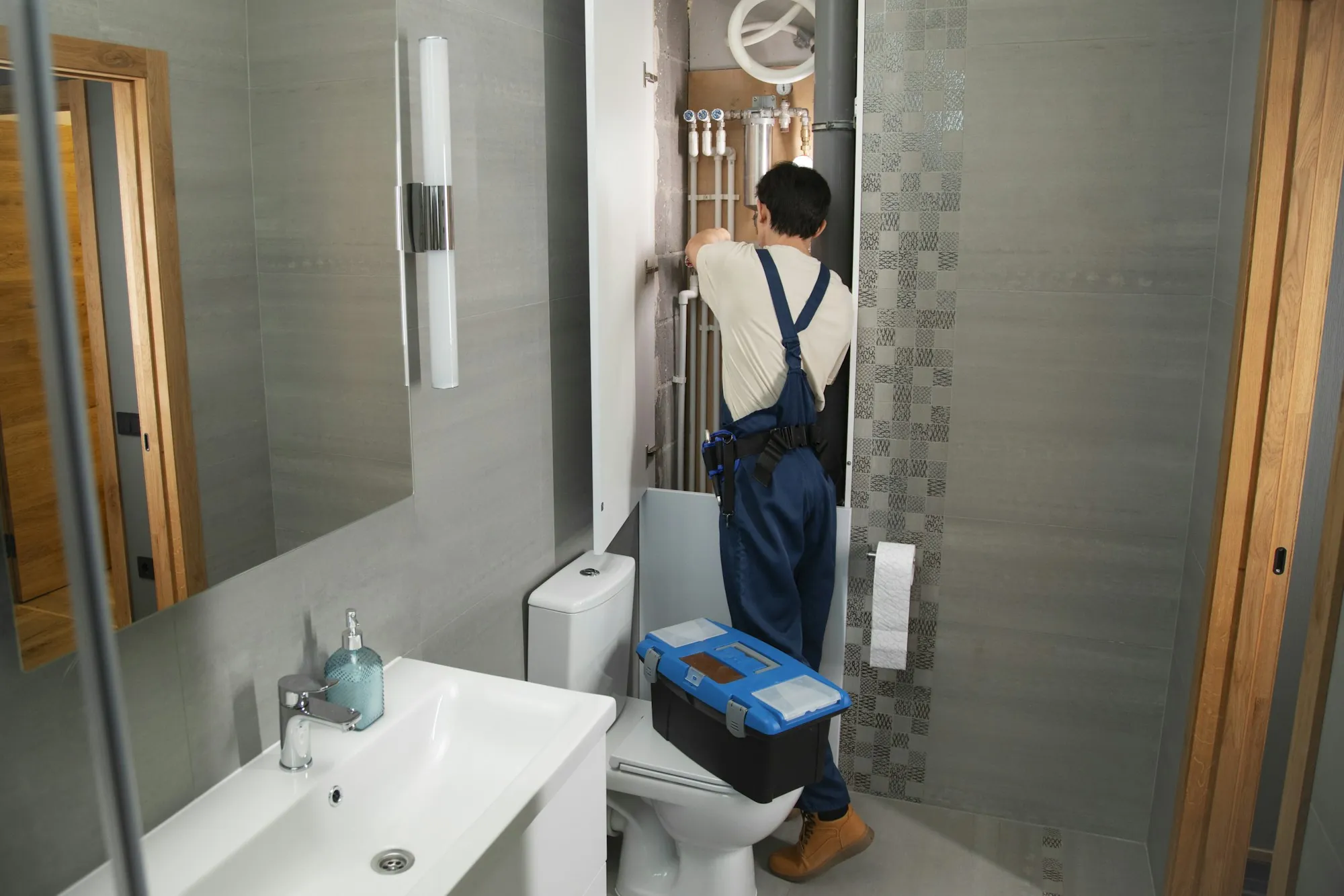 Water Filter Repair & Maintenance in Fountain Valley, CA Plumber in overalls working on bathroom plumbing