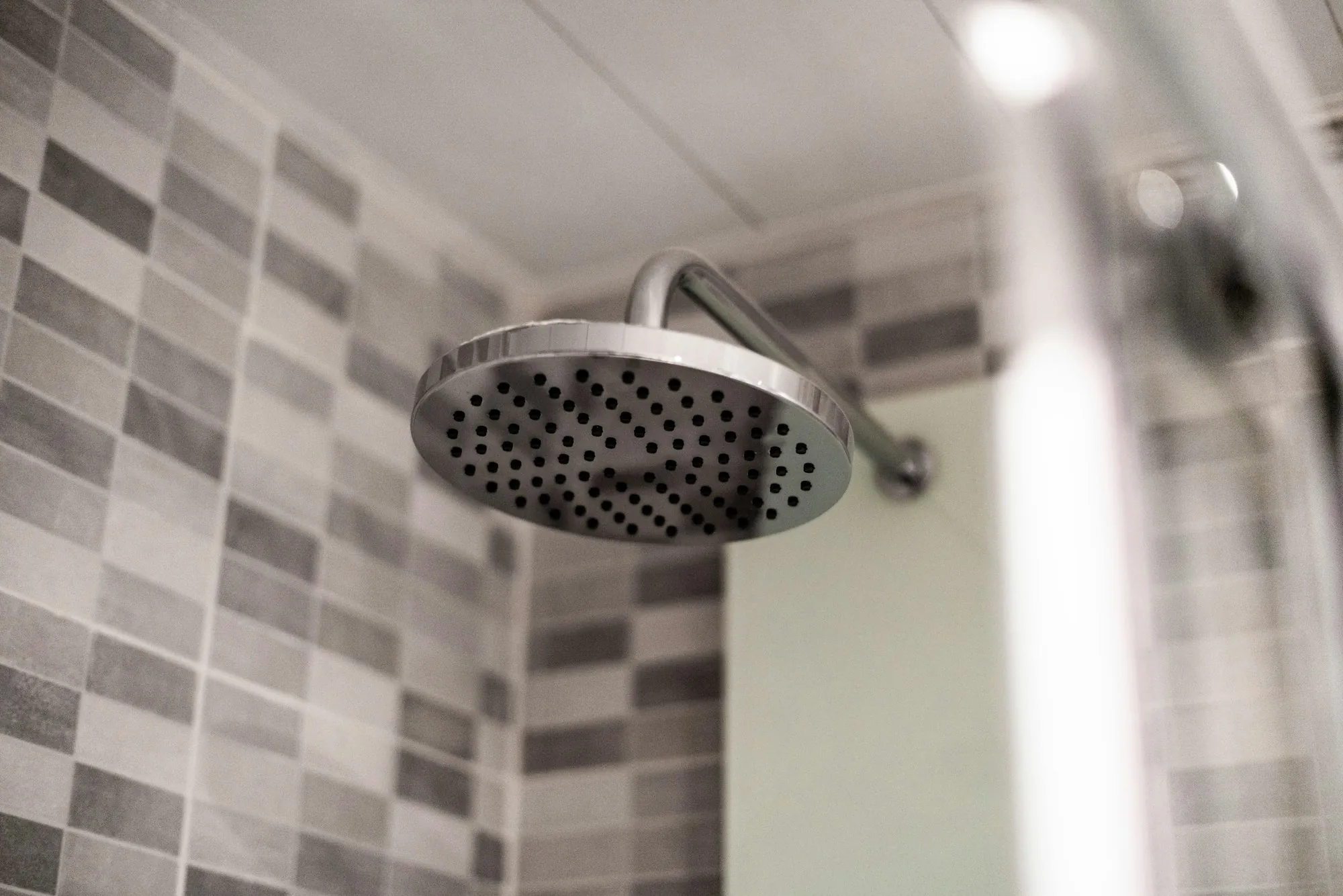 Stainless steel shower head in a tiled bathroom