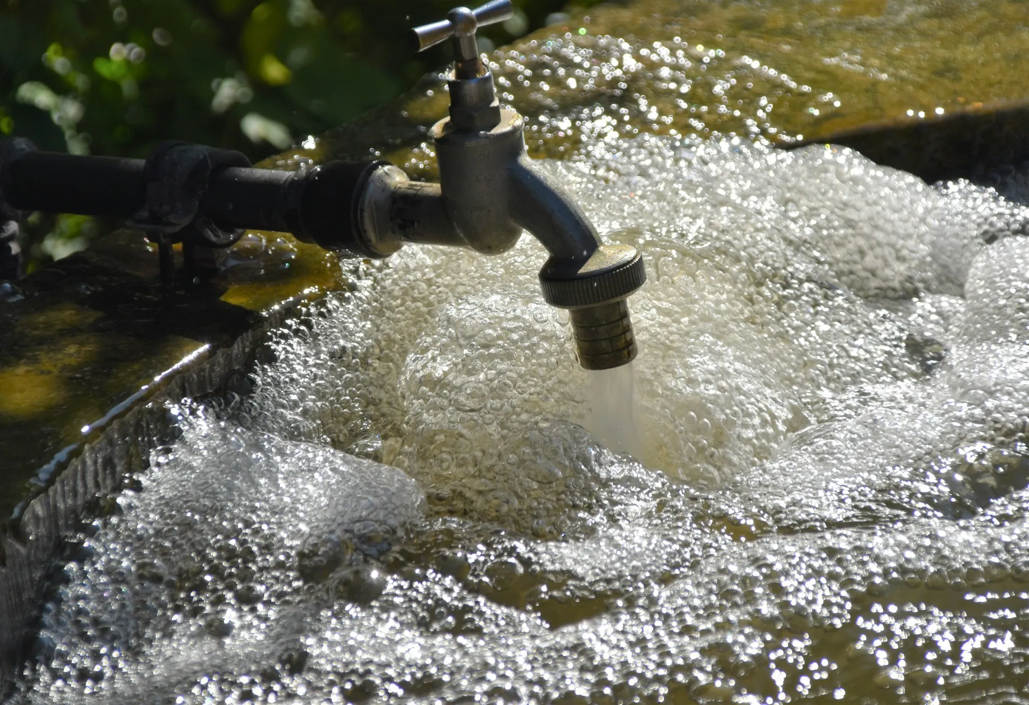 Water rushing from a metal tap into a basin