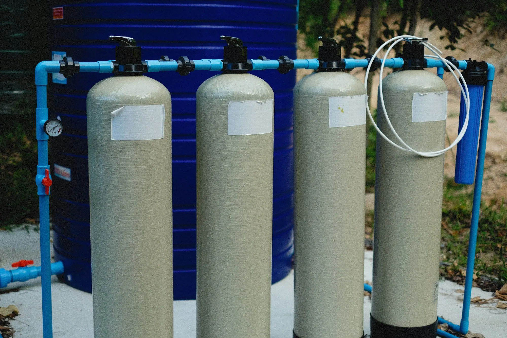 Row of water treatment tanks connected with blue piping